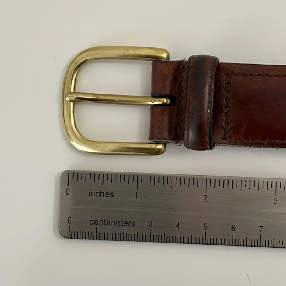 Brown leather belt with center stitch details. Size 32. ‎ Solid brass buckle.
